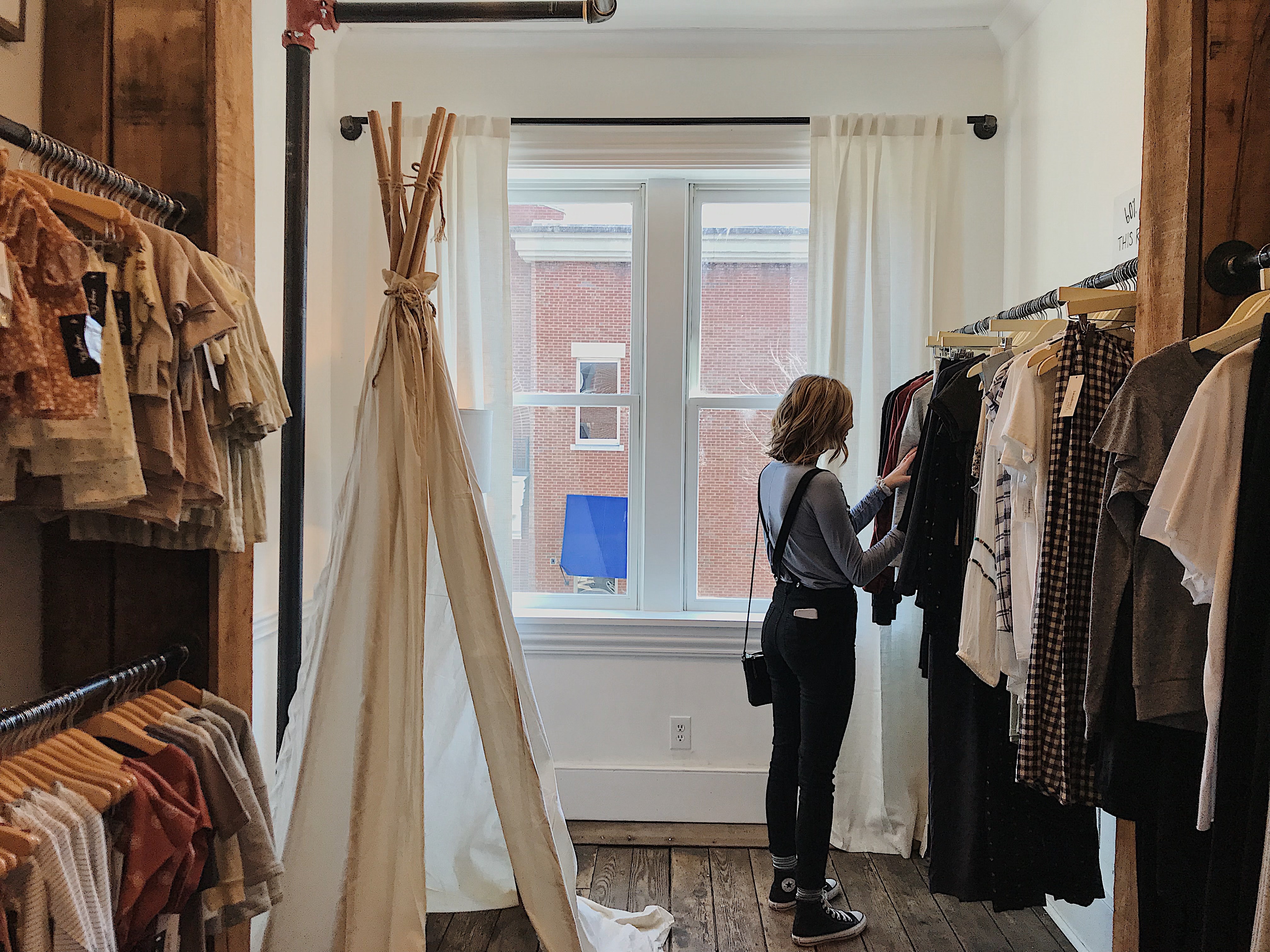 A young woman browsing a clothing store.