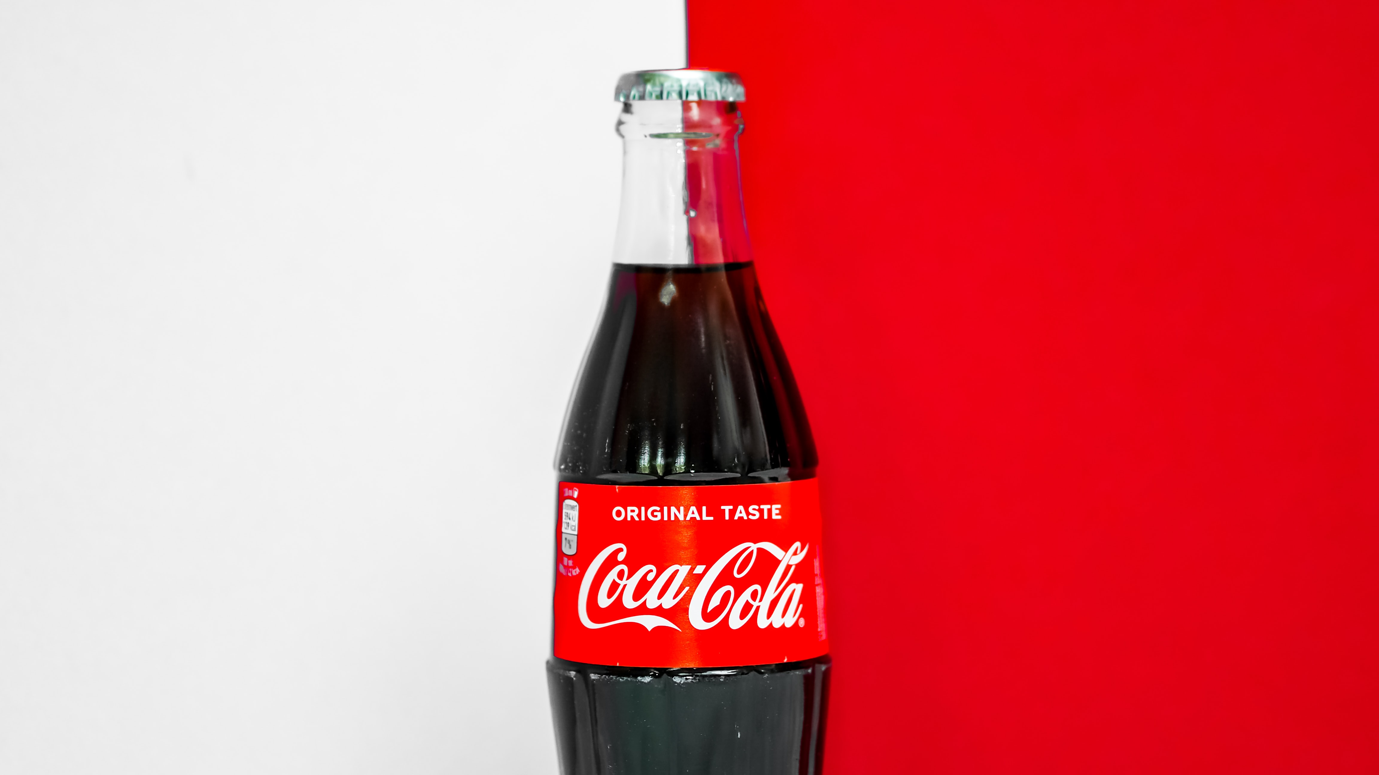 Coca-Cola bottle on half white, half red background.